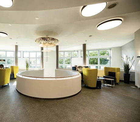 Lobby im MEDIAN Hotel Lehrte mit Rundung in der Mitte und gelben Ohrensesseln