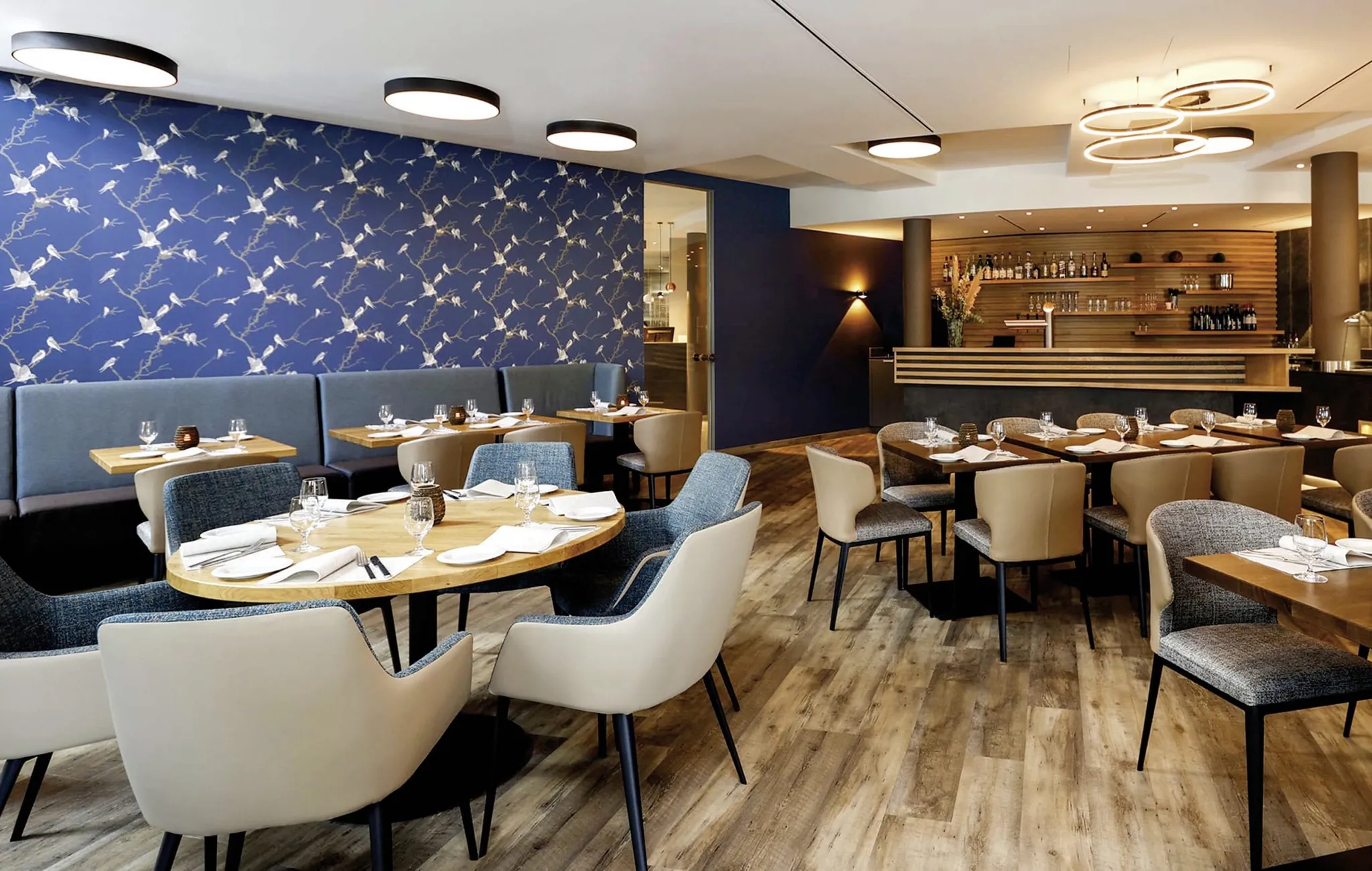 Restaurant im MEDIAN Hotel Lehrte mit blauer Vogeltapete und grauen Sesseln