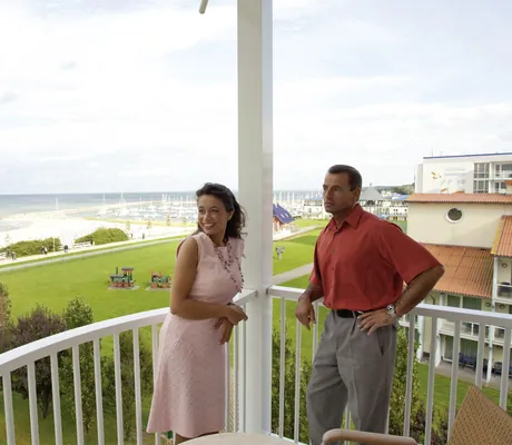 Paar auf weiß gestrichenem Balkon des MORADA Strandhotel mit Blick auf die Ostsee