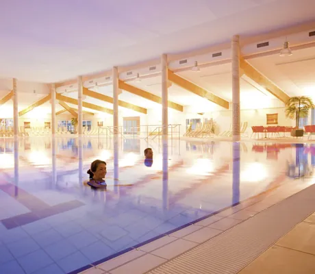 Paar schwimmt im lichtdurchfluteten Indoorpool des MORADA Strandhotel