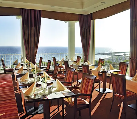 Restaurant mit rot gestreiften Sitzmöbeln und Blick auf die Ostsee im MORADA Strandhotel