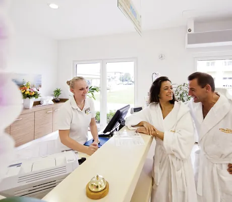 Paar in weißen Bademänteln an der Spa-Rezeption des MORADA Strandhotel