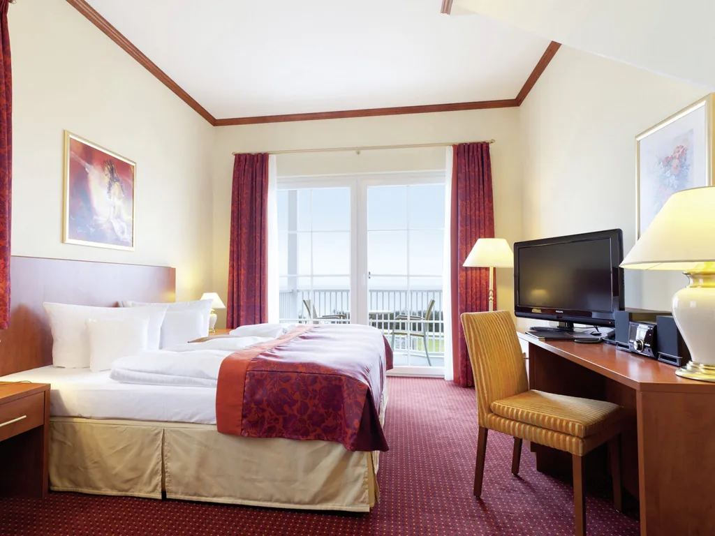 Zimmer mit rotem Teppich und gestreift gepolstertem Stuhl im MORADA Strandhotel