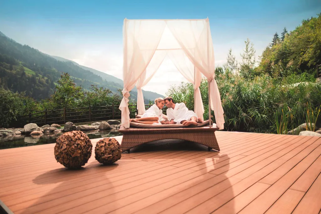 Pärchen liegt in Bademänteln auf Ruheinsel im Naturbadeteich im Quellenhof Luxury Resort Passeier