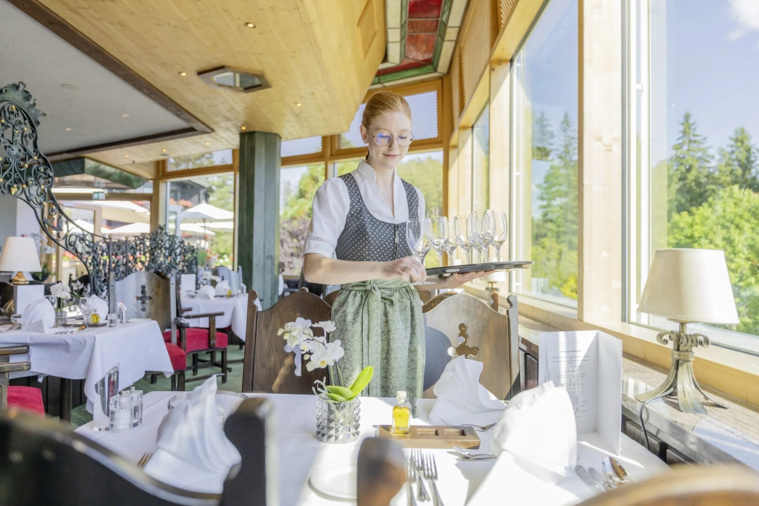 Junge Frau in Tracht deckt die Restauranttische im Wellnesshotel Vier Jahreszeiten am Schluchsee