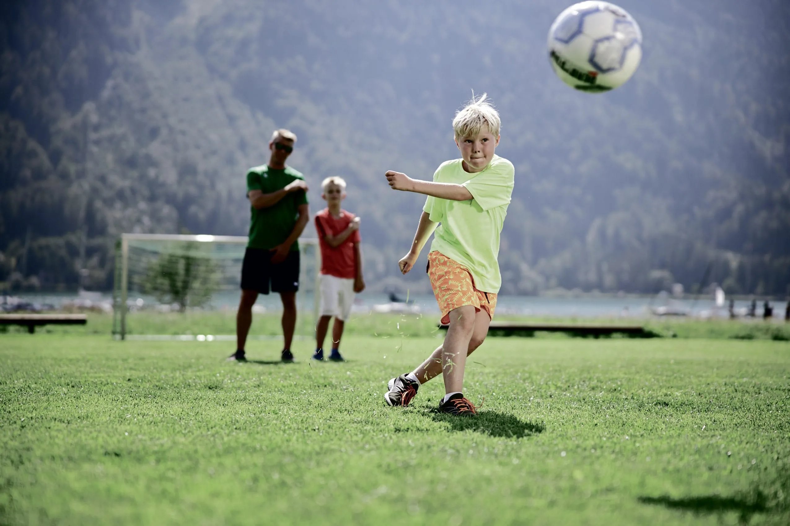 Junge in T-Shirt und Shorts beobachtet fliegenden Fussball in der Fussballschule des Familienresort Buchau am Achensee