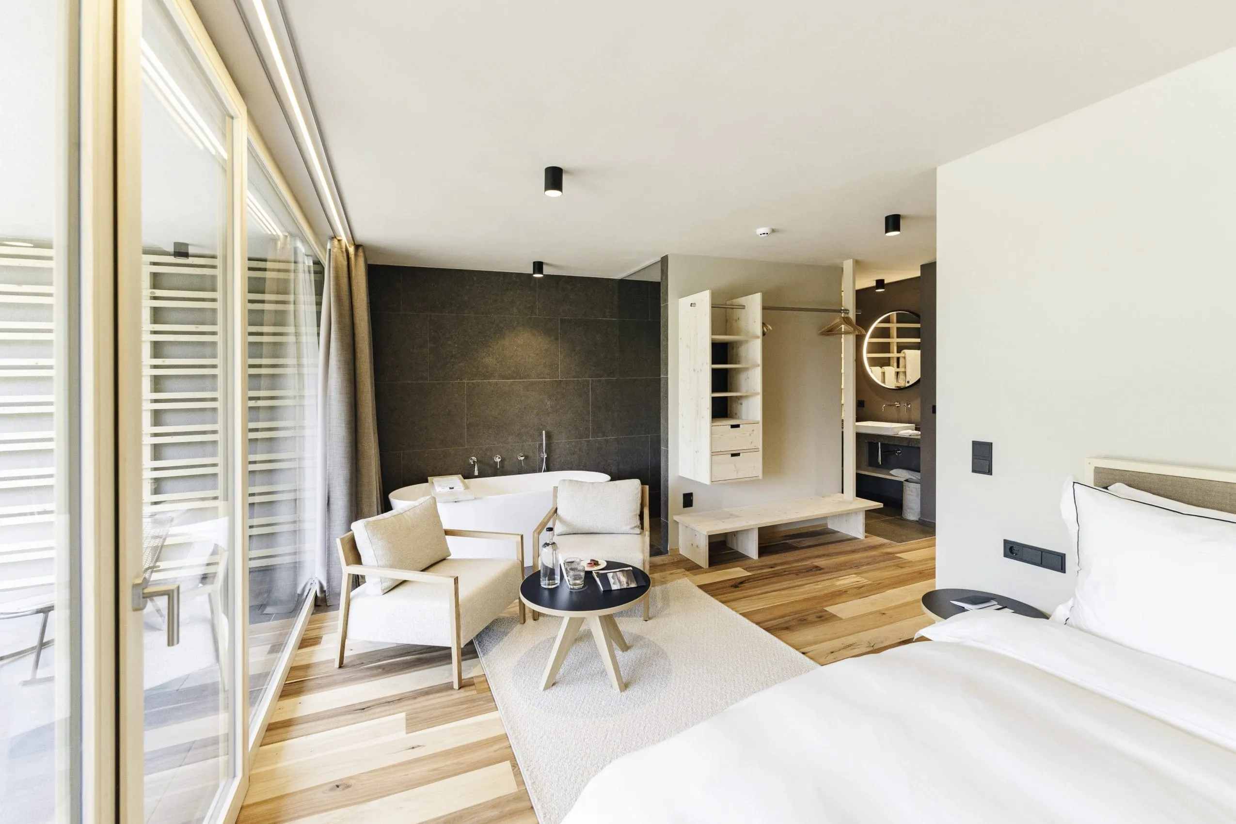 Suite in Naturmaterialien mit Badewanne und Fensterfront im Sensoria Dolomites