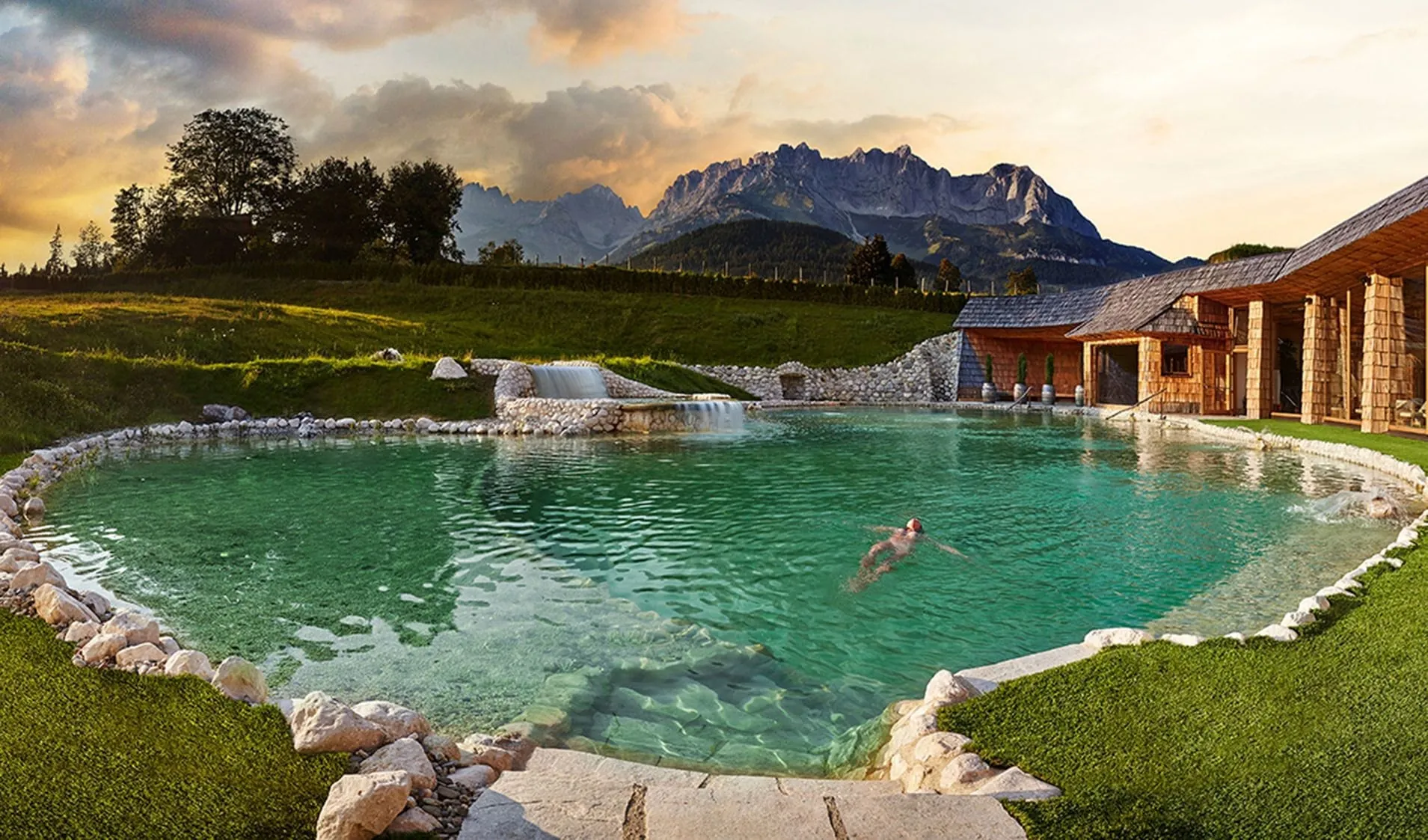 Naturbadesee mit Natursteinfassung vor Bergkulisse im Stanglwirt