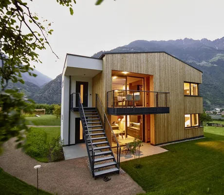 Von innen beleuchtetes Chalethaus in Naturns in der Abenddämmerung