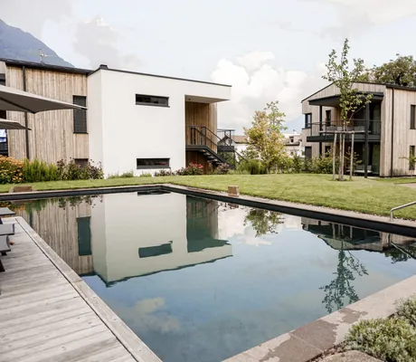 Blick auf die Chalethäuser der Cirna Gentle Luxury Lodges in Südtirol mit Biopool im Vordergrund