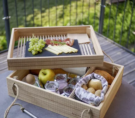 Reich bestückter Frühstückskorb aus Holz mit regionalen Produkten