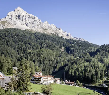 Aussenaufnahme des Family Adventure Hotel Maria in Obereggen vor Berg und Wald