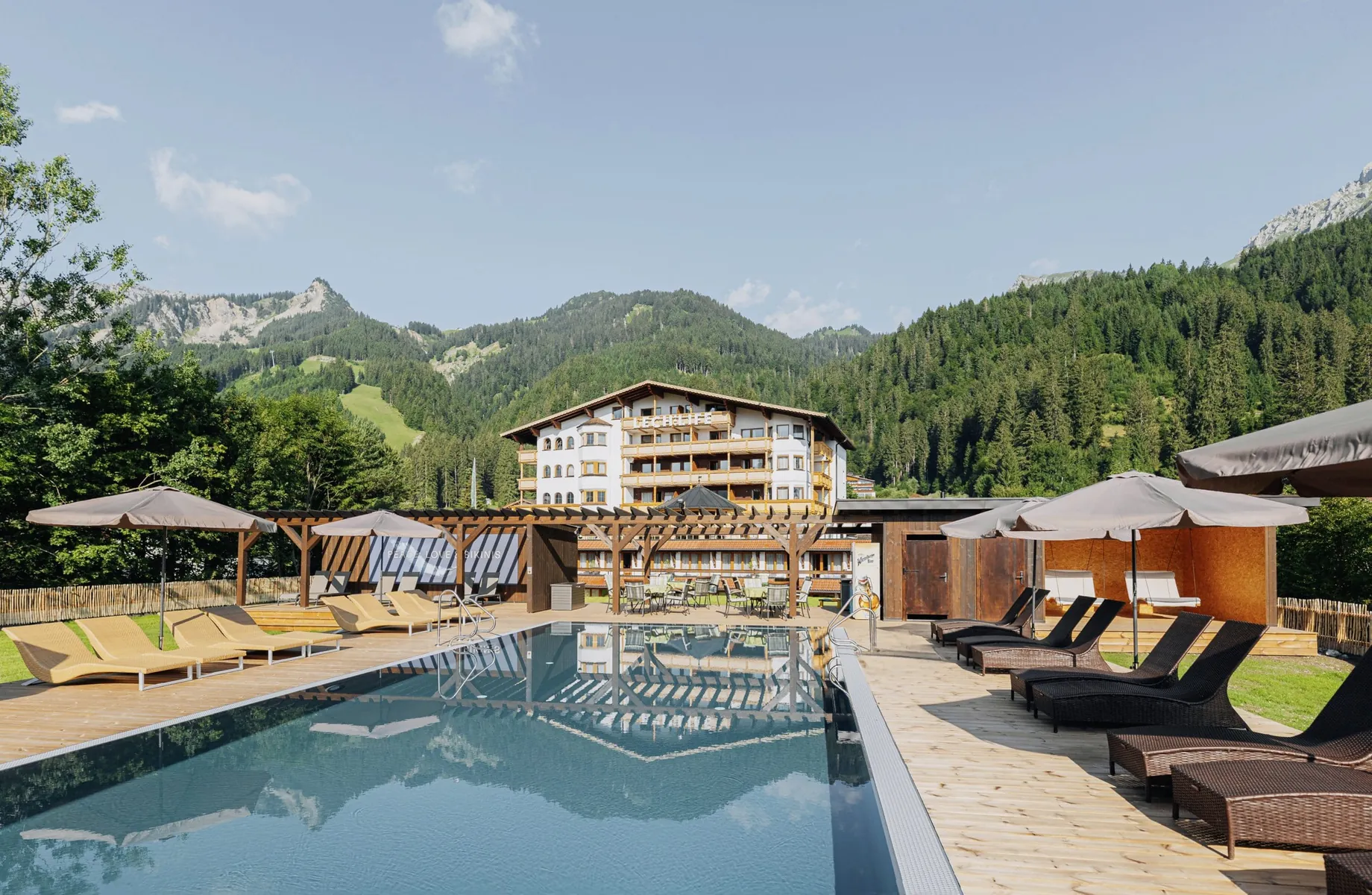 Blick auf das Lechlife Travelhouse in Wängle in Österreich mit Outdoorpool im Vordergrund