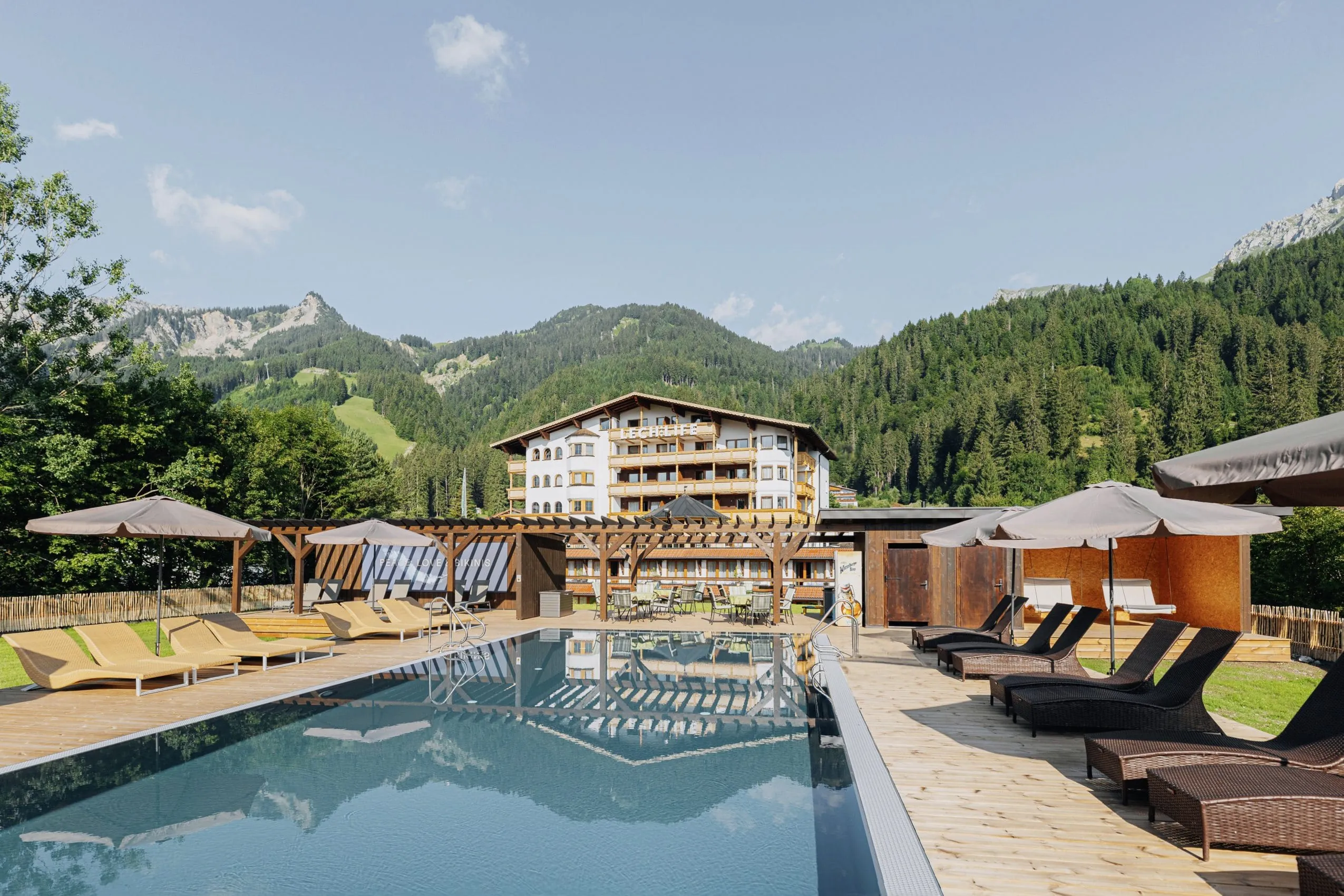 Blick auf das Lechlife Travelhouse in Wängle in Österreich mit Outdoorpool im Vordergrund
