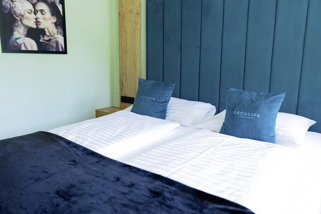 Doppelbett im Lechlife Travelhouse mit blauen Kissen und blauer Tagesdecke