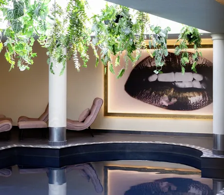 Indoorpool im Lechlife Travelhouse mit von der Decke hängenden Grünpflanzen und modernen Fotografien an den Wänden