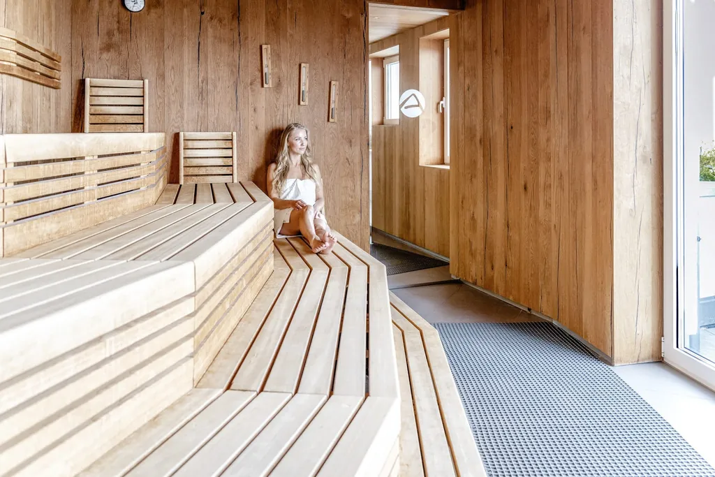 Junge Frau mit Handtuch entspannt in der Sauna des Strandhotels DAS AHLBECK Hotel & Spa