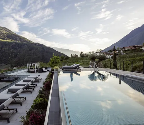 Blick auf Rooftop-Pool des AVIDEA mit Sonnenliegen und Bergen im Hintergrund