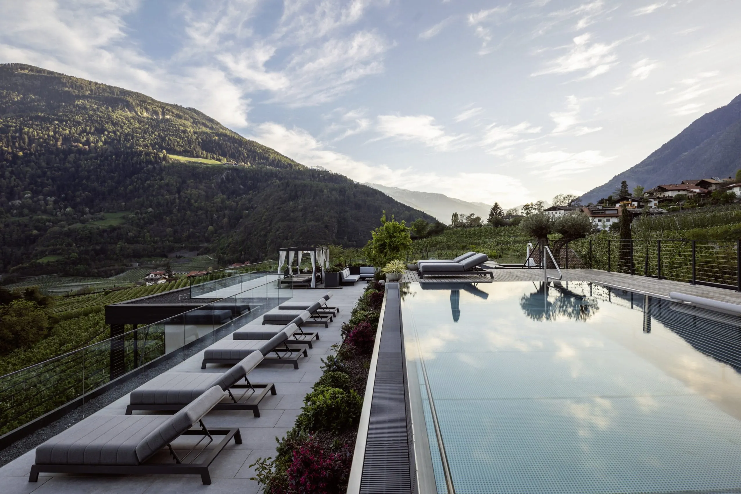 Blick auf Rooftop-Pool des AVIDEA mit Sonnenliegen und Bergen im Hintergrund