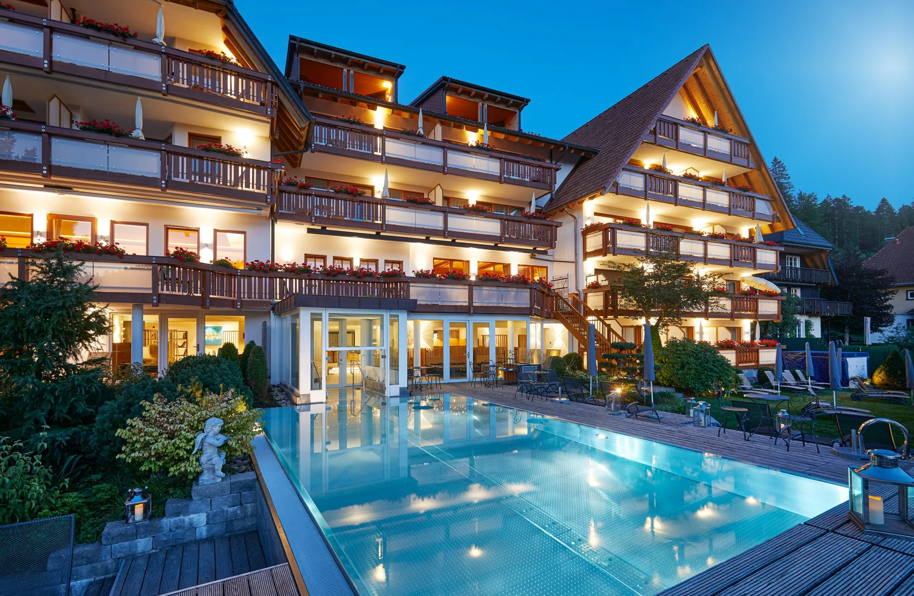 Außenaufnahme des Wellnesshotel Bergfried mit Blick auf den Pool bei abendlicher Beleuchtung