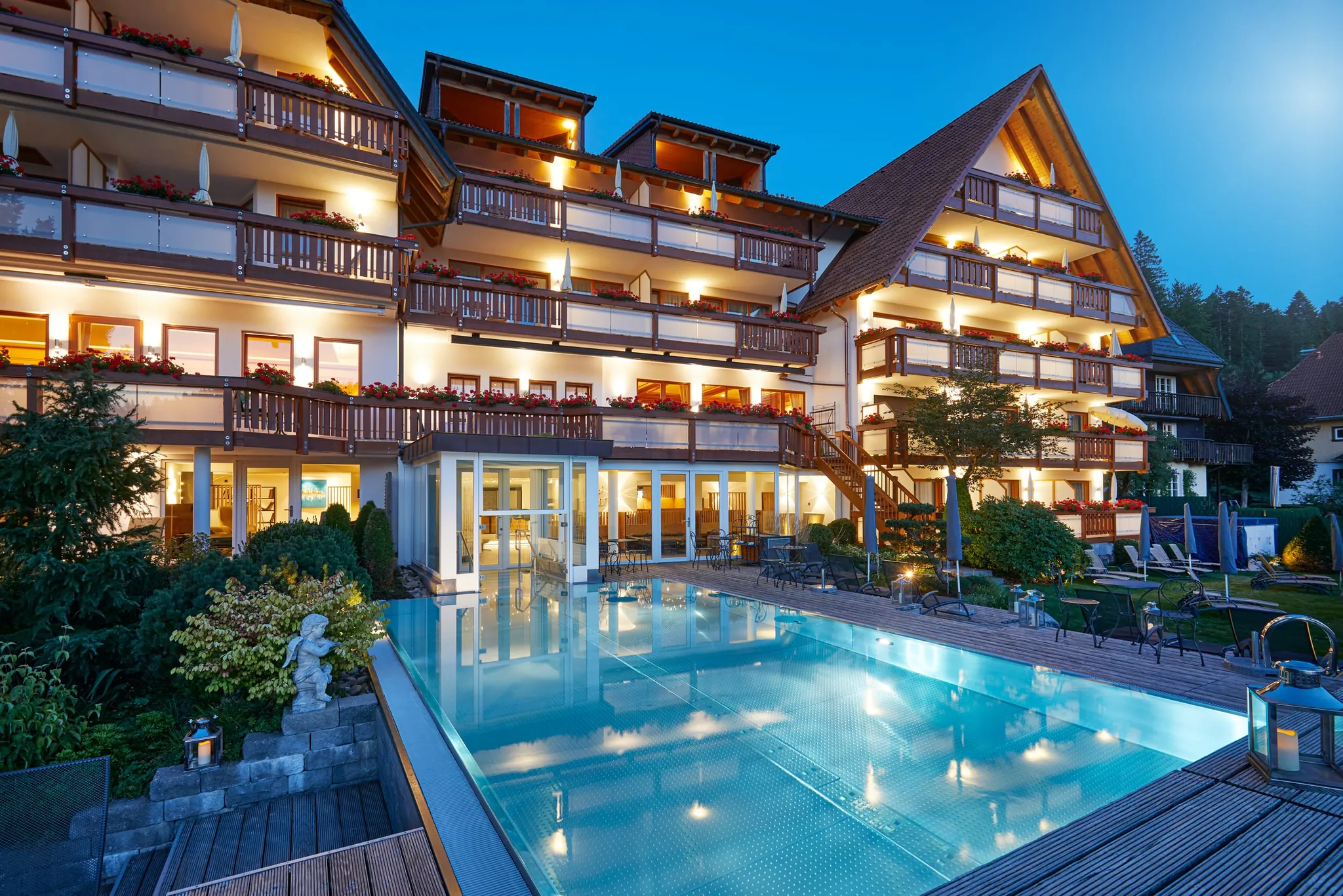 Außenaufnahme des Wellnesshotel Bergfried mit Blick auf den Pool bei abendlicher Beleuchtung