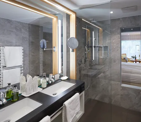 Badezimmer des Bergfried Hotels mit marmorierter Wand, Regendusche und großem Spiegel