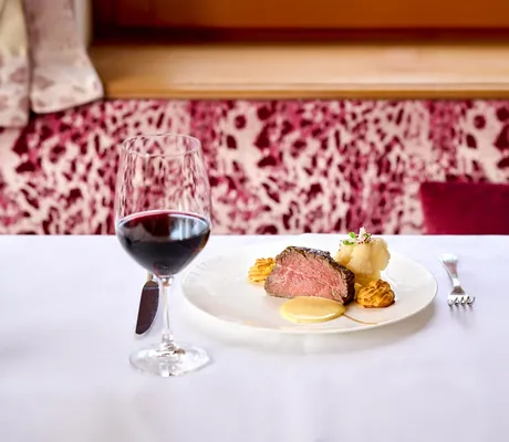 Blick auf schön angerichtete Speise und Rotweinglas im Bergfried Hotel