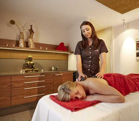 junge Frau liegt auf Massageliege und bekommt Hot Stone Massage