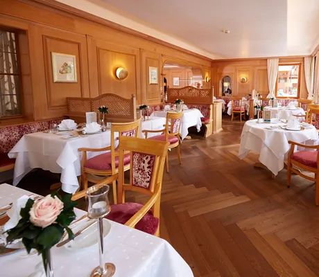 Restaurantbereich mit gepolsterten Holzbänken und -stühlen des Bergfried Hotels