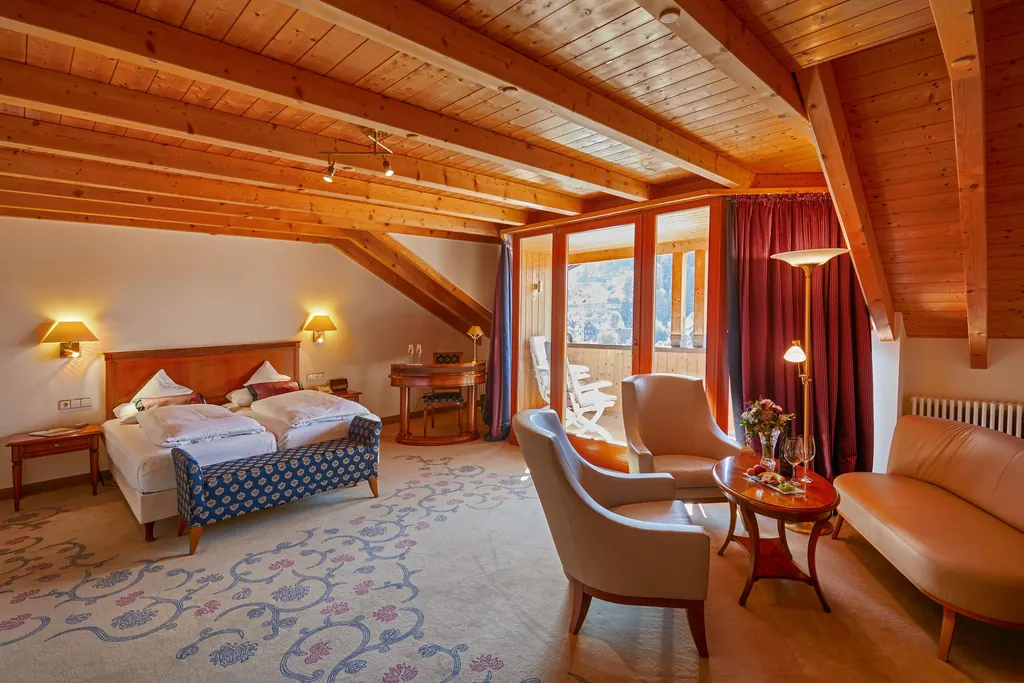 geräumiges Zimmer im Bergfried Hotel mit Teppichbodenverzierung, Doppelbett und beigefarbenen Sesseln