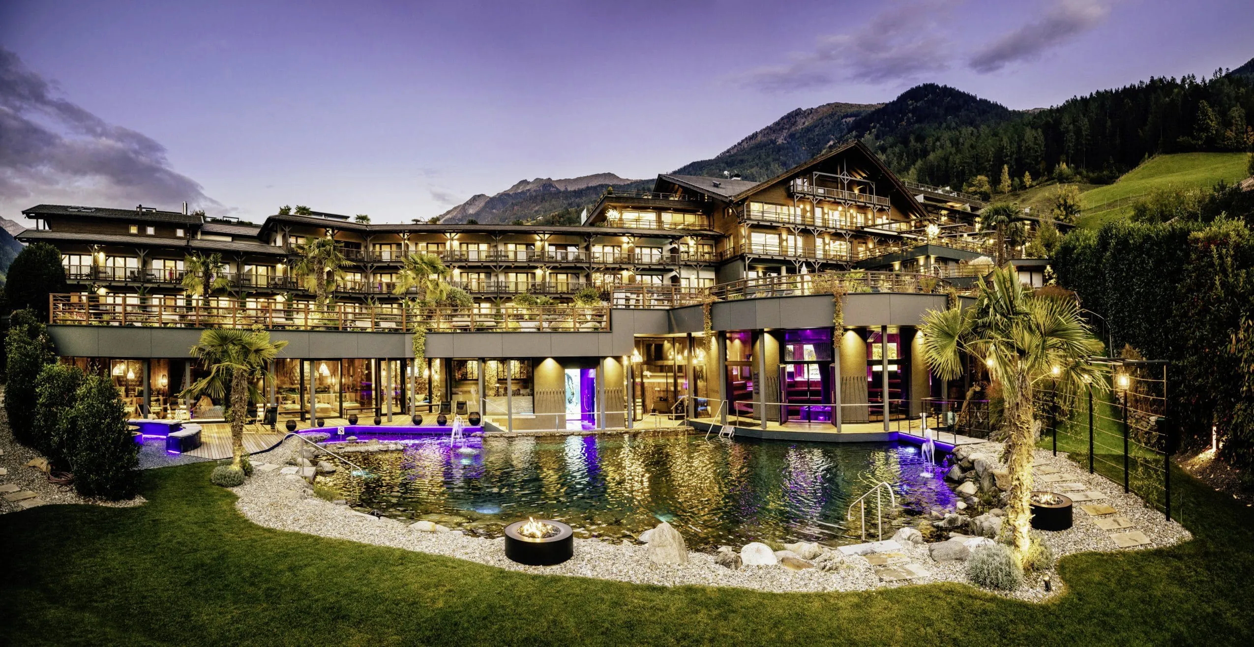 Außenansicht des Andreus Resort mit Naturbadeteich bei Abenddämmerung