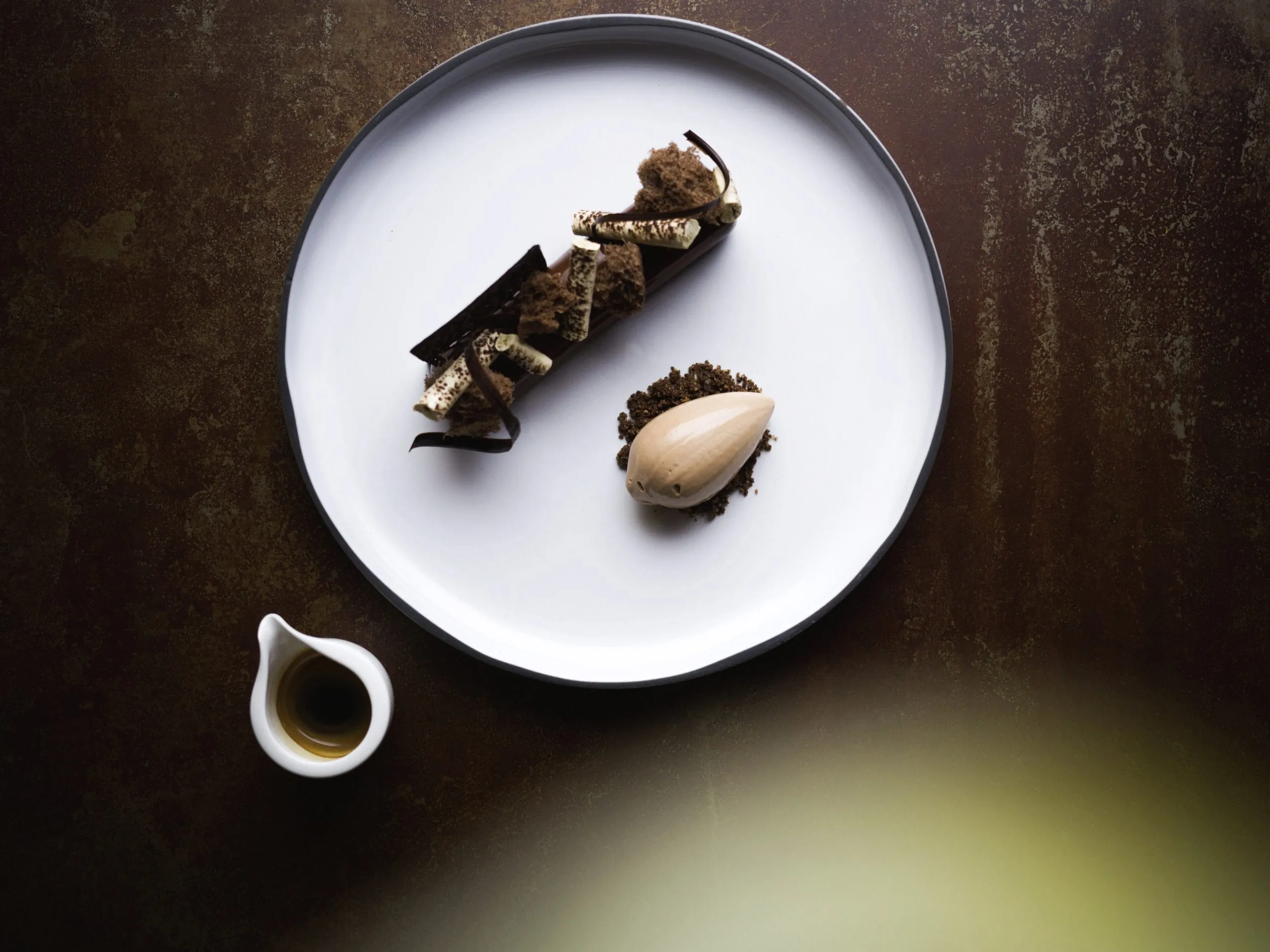 weißer Teller auf braunem Untergrund mit Dessert im AVIDEA