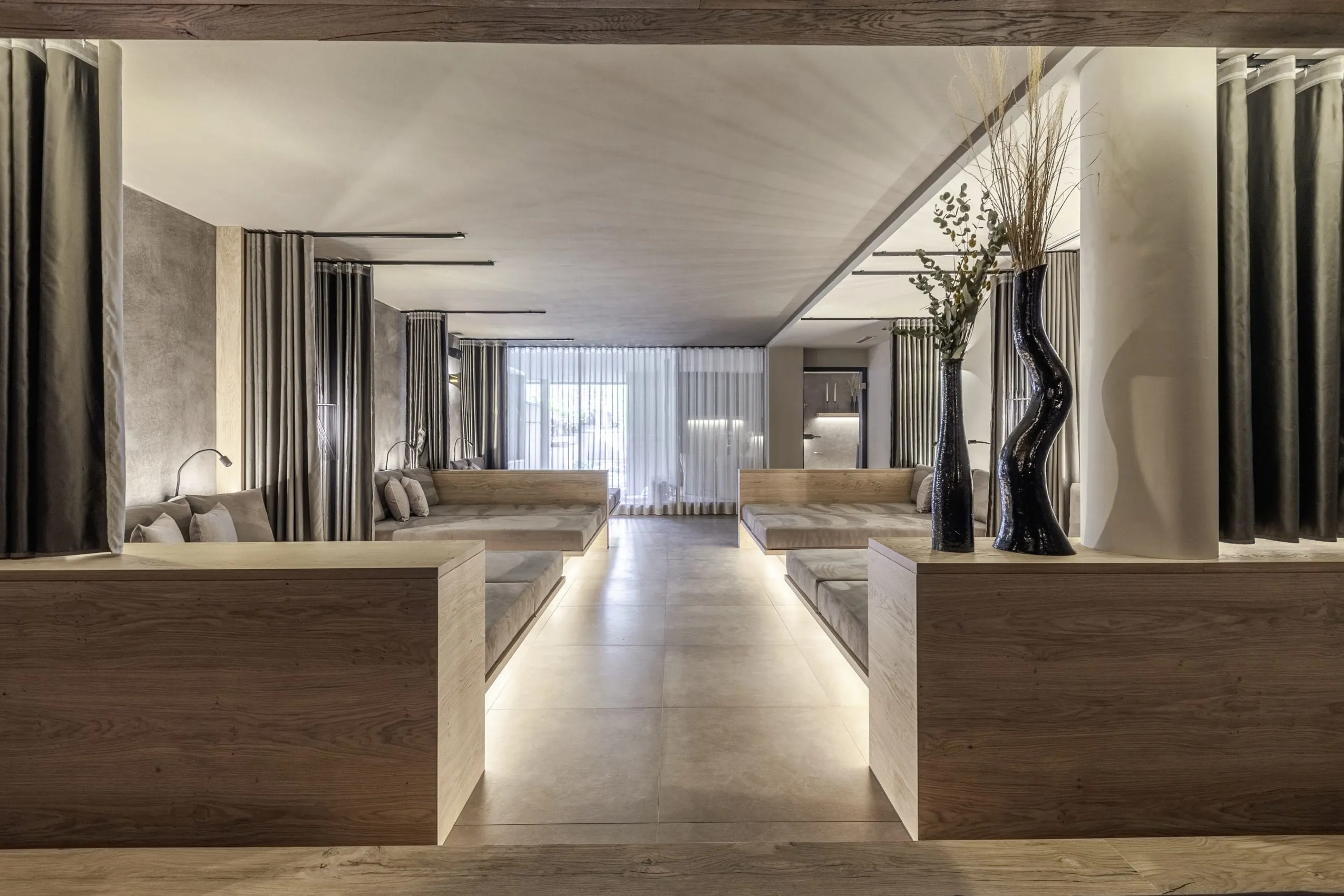 Ruhebereich mit abtrennbaren sandfarbenen Kojen und großen schwarzen Vasen im AVIDEA