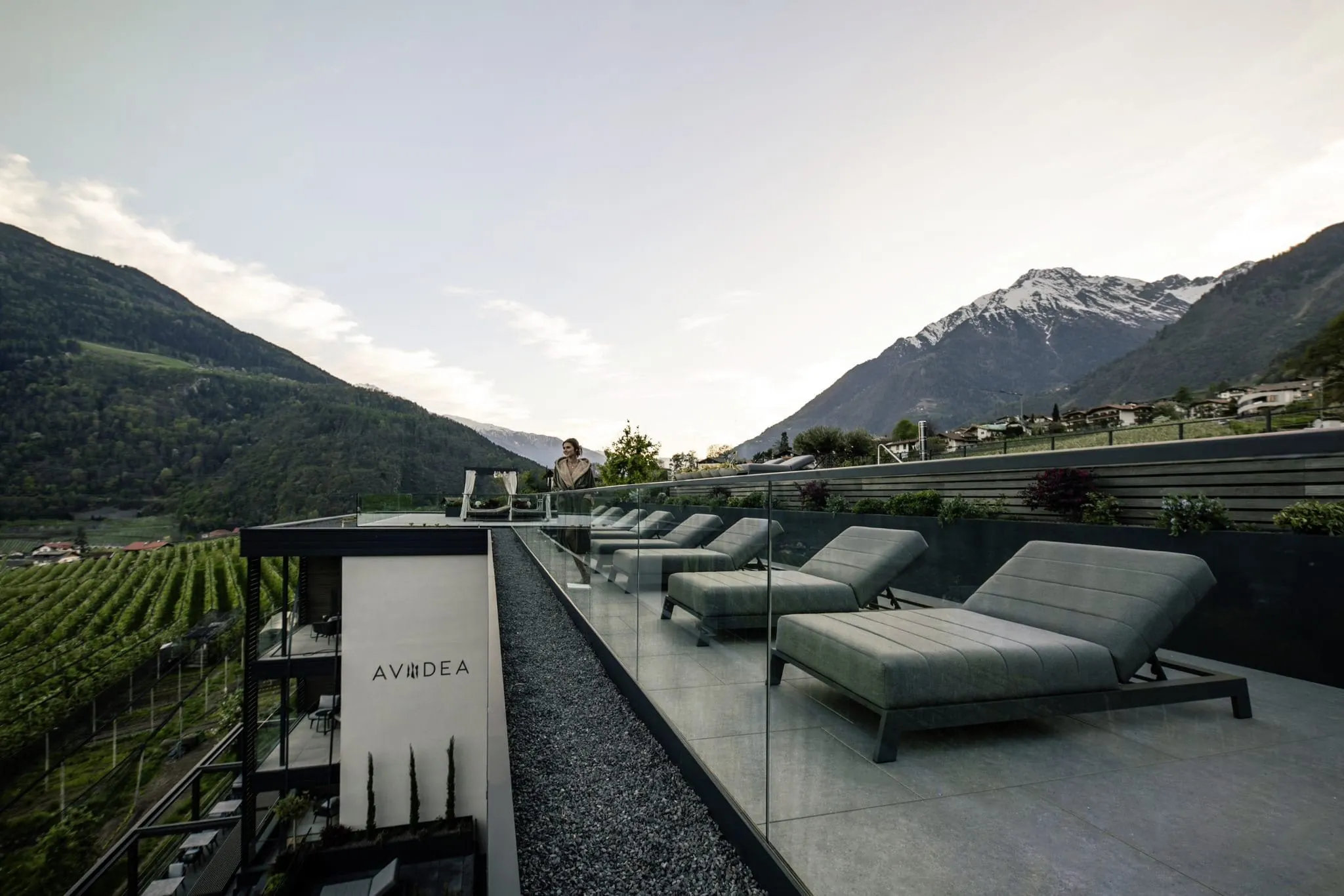 Frau im Bademantel auf Skyterrasse mit Liegen im AVIDEA