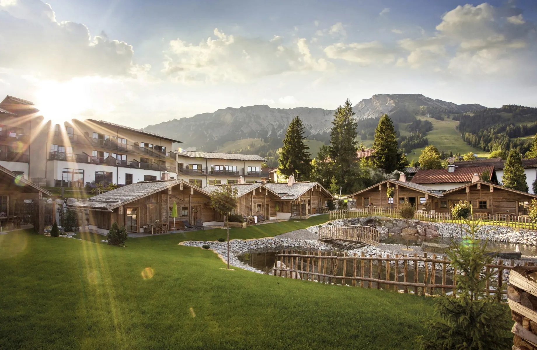 Blick auf die Alpin Chalets Oberjoch mit Naturteich und Bergpanorama im Hintergrund