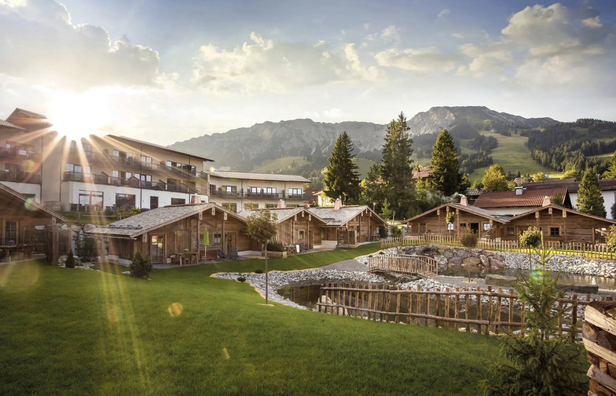 Blick auf die Alpin Chalets Oberjoch mit Naturteich und Bergpanorama im Hintergrund