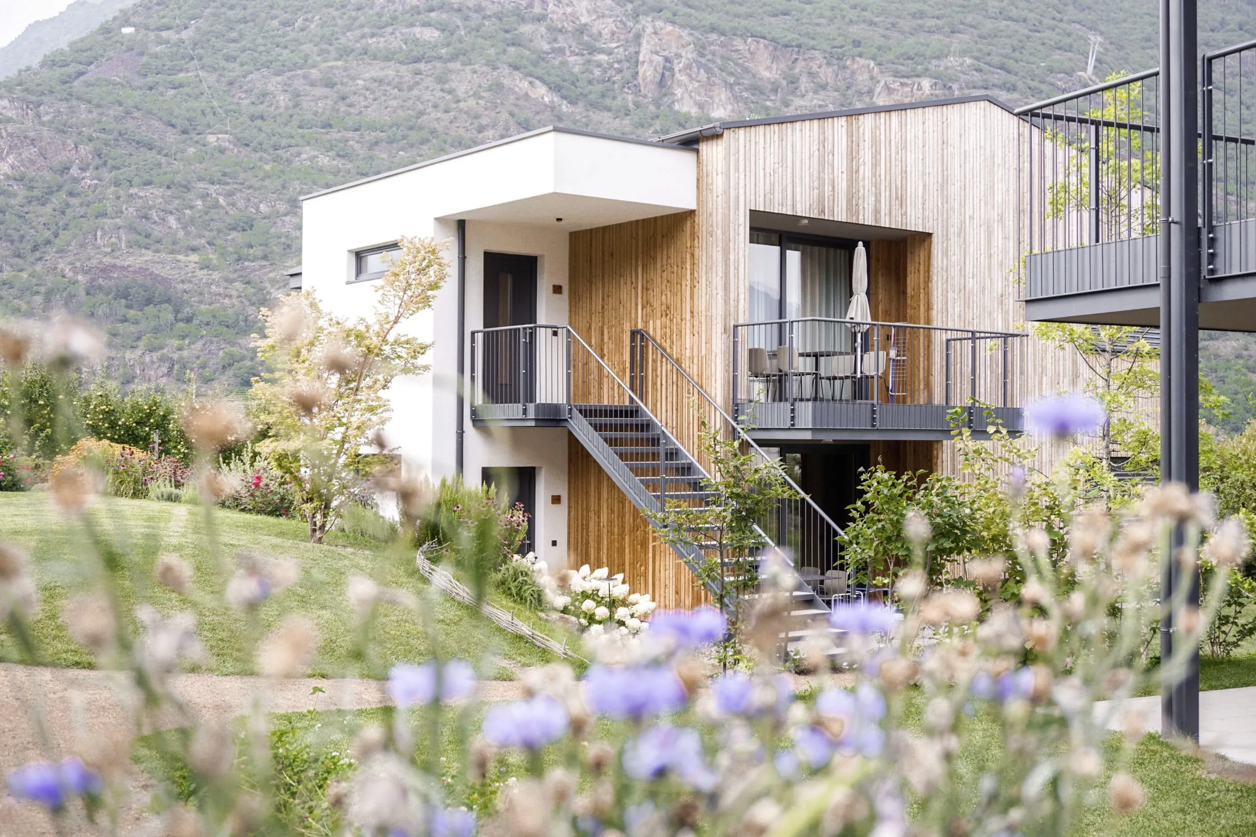 Blick auf die Cirna Gentle Luxury Lodges mit Balkon, Blumen im Vordergrund