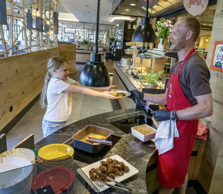 junges Mädchen nimmt freudig einen vollen Teller vom Küchenchef des Hotel & Resort Landhaus zur Ohe entgegen