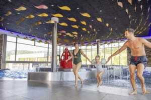 Vater, Mutter, Tochter Hand in Hand im Badeanzug im Poolbereich des Familotel Schreinerhof