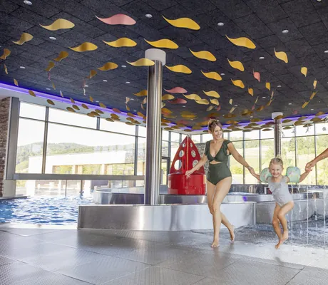 Vater, Mutter, Tochter Hand in Hand im Badeanzug im Poolbereich des Familotel Schreinerhof