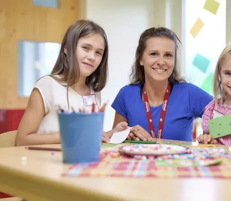 zwei Mädchen mit Kinderbetreuerin basteln im Familotel Schreinerhof