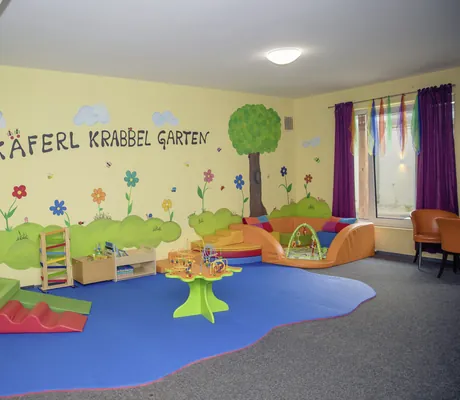 Krabbelecke mit blauem Teppich und Kleinkindspielzeug im Familotel Schreinerhof