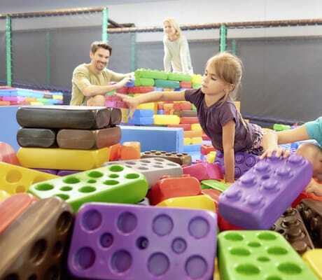 Eltern spielen mit zwei Mädchen mit großen bunten Legos im Familotel Schreinerhof