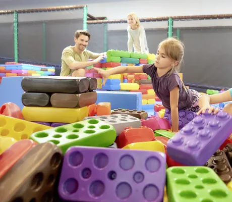 Eltern spielen mit zwei Mädchen mit großen bunten Legos im Familotel Schreinerhof