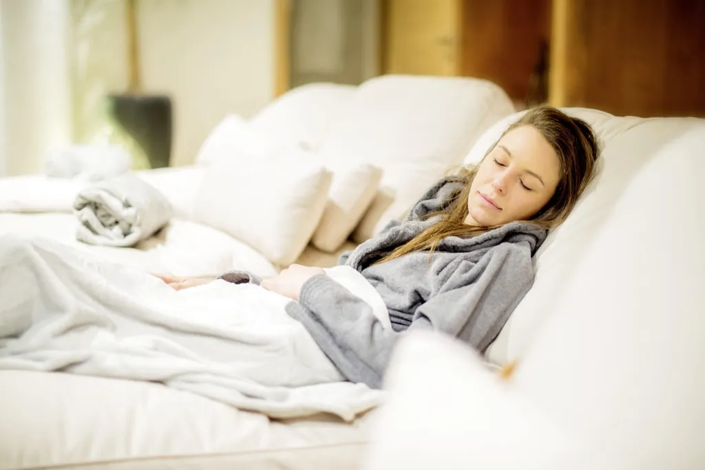 Junge Frau liegt auf mit Kräutern gefülltem Ruhebett im Wellnessbereich des Chalet Stern