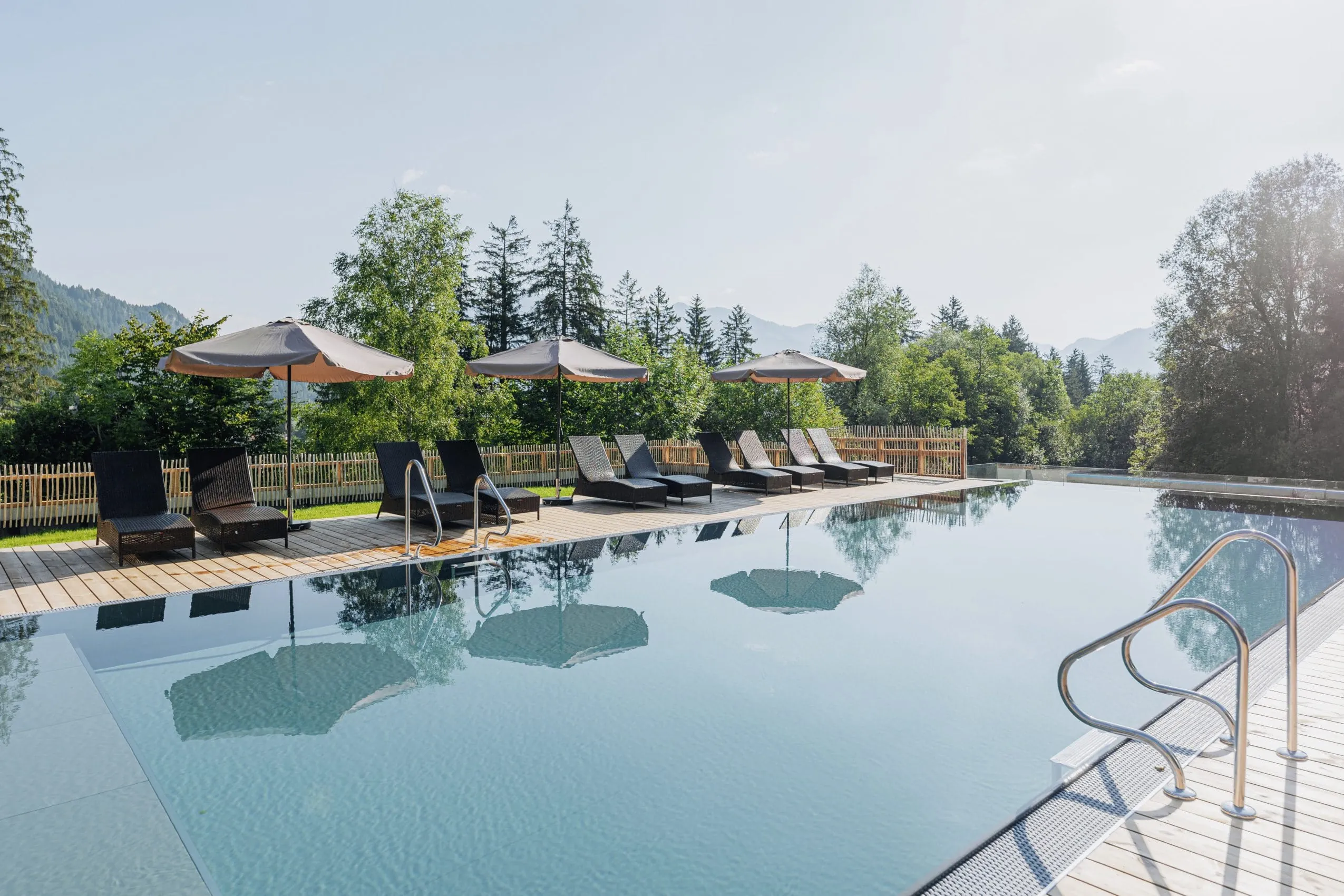 Outdoor-Infinitypool mit Liegen und Ausblick in die umgebende Berglandschaft im LechLife Travelhouse
