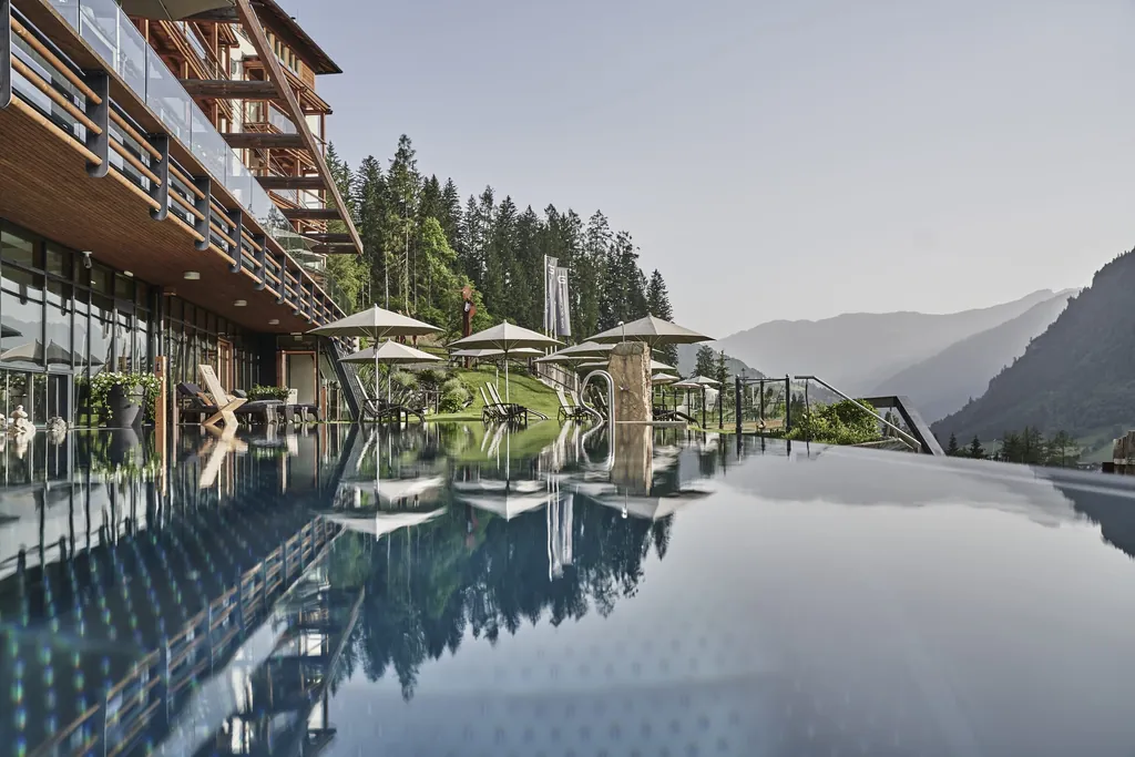 Outdoor-Infinitypool des Wellnesshotels DAS.GOLDBERG mit Spiegelungen auf der Wasseroberfl&auml;che