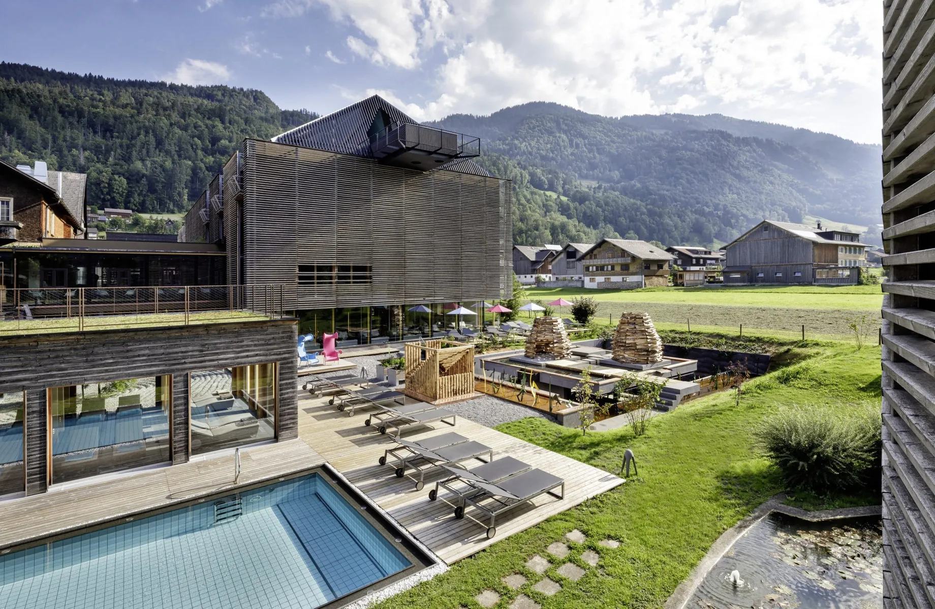 Außenansicht des GAMS zu zweit mit Outdoorpool, Sonnenliegen und Bregenzer Wald im Hintergrund