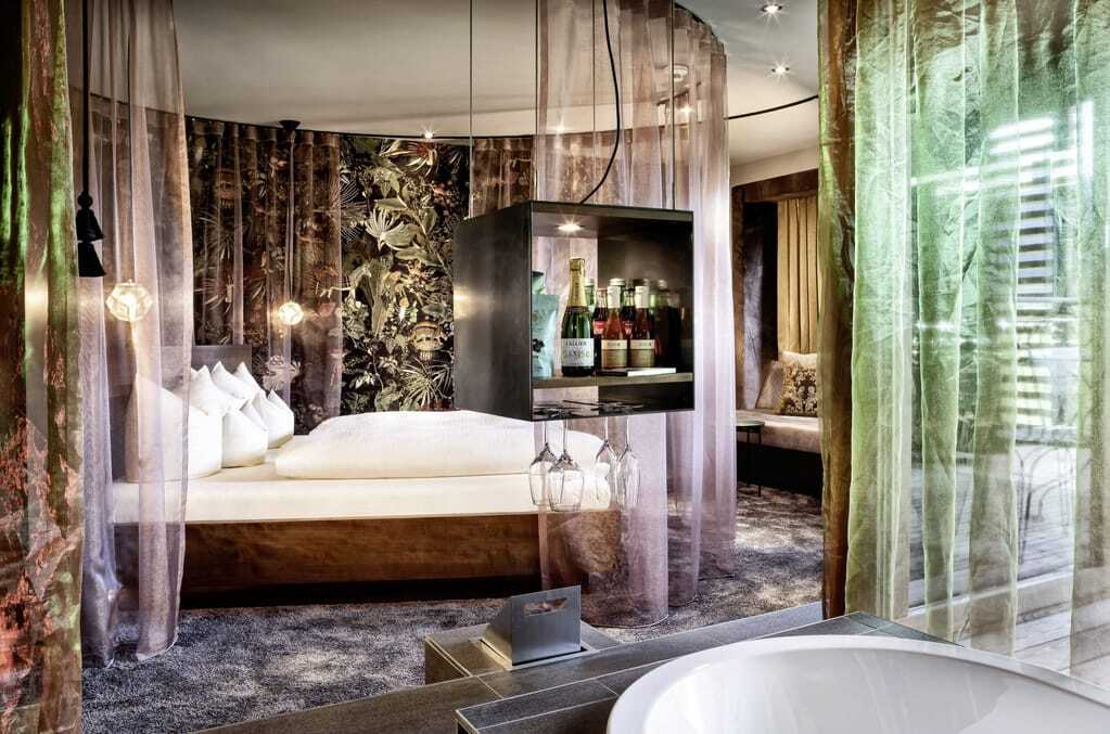 Blick in die Kuschelsuite im Kokon des GAMS zu zweit mit Himmelbett, rosa Vorhängen und kleiner Minibar