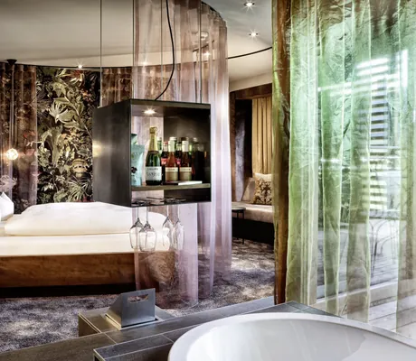 Blick in die Kuschelsuite im Kokon des GAMS zu zweit mit Himmelbett, rosa Vorhängen und kleiner Minibar